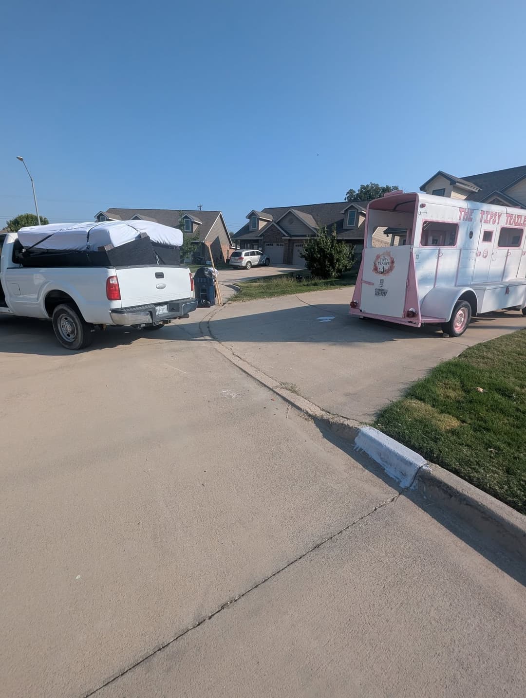 Food truck parked by a residential street, with a pickup truck nearby on a sunny day.