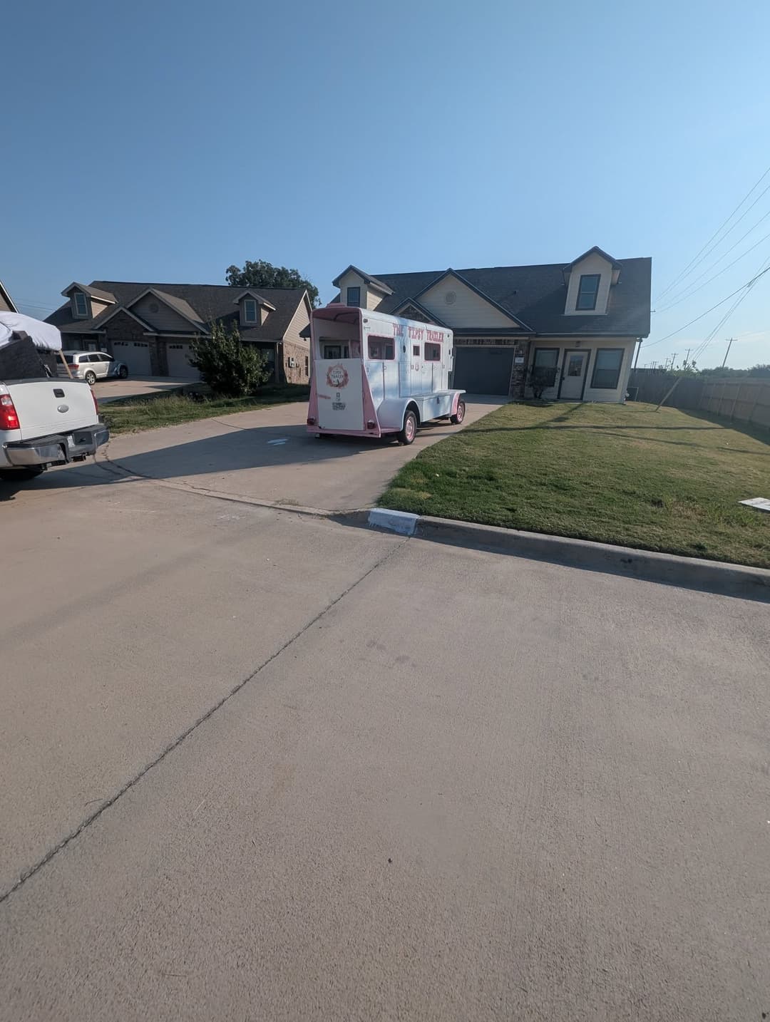 Ice cream truck parked in driveway of suburban home on a clear sunny day.