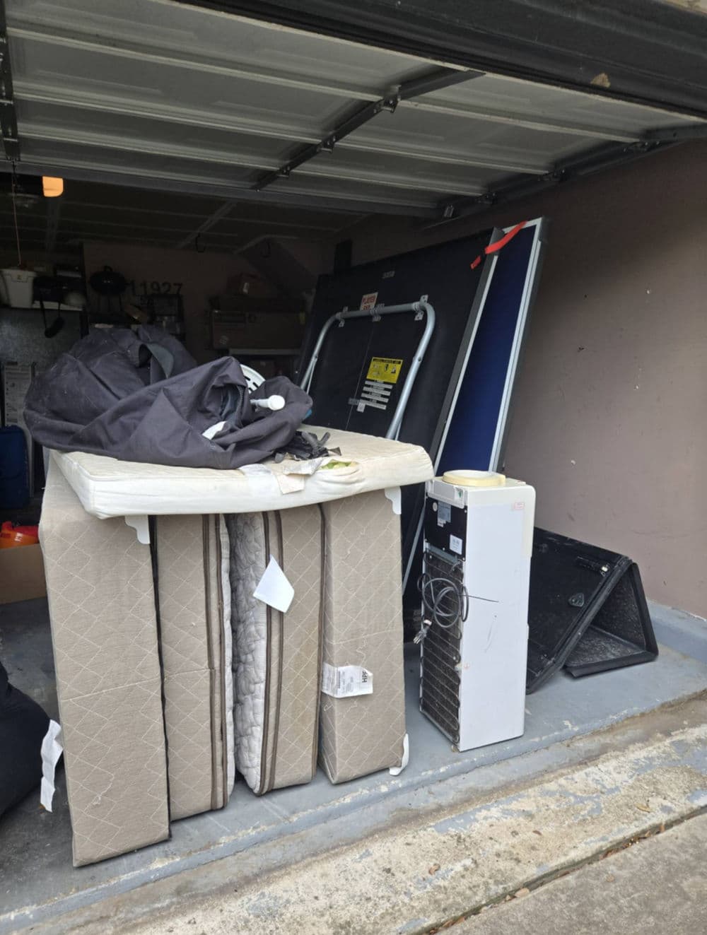 Storage garage filled with old mattresses, appliances, and miscellaneous items.